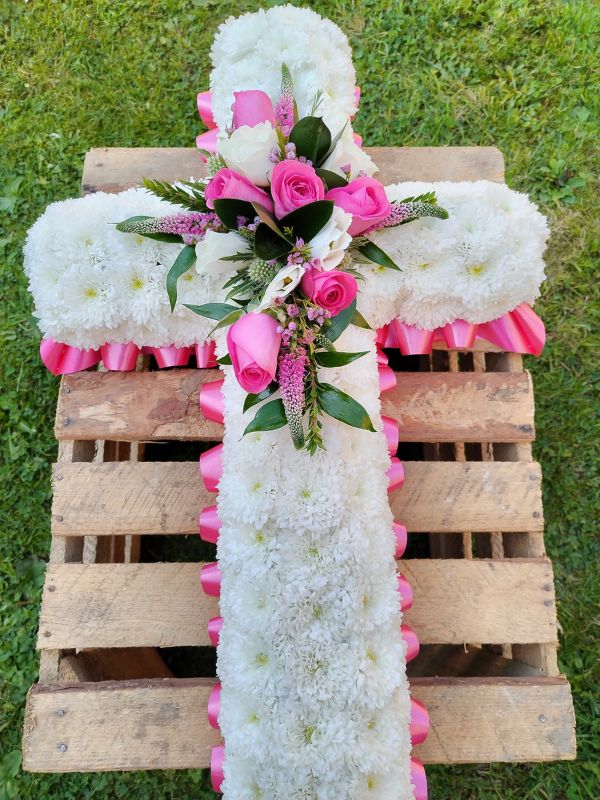 Floriana Floristry Funeral Cross with white flower background and pink roses and ribbon
