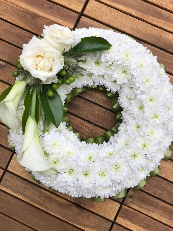 Image of white flower funeral wreath with white roses and white cala lilies on top